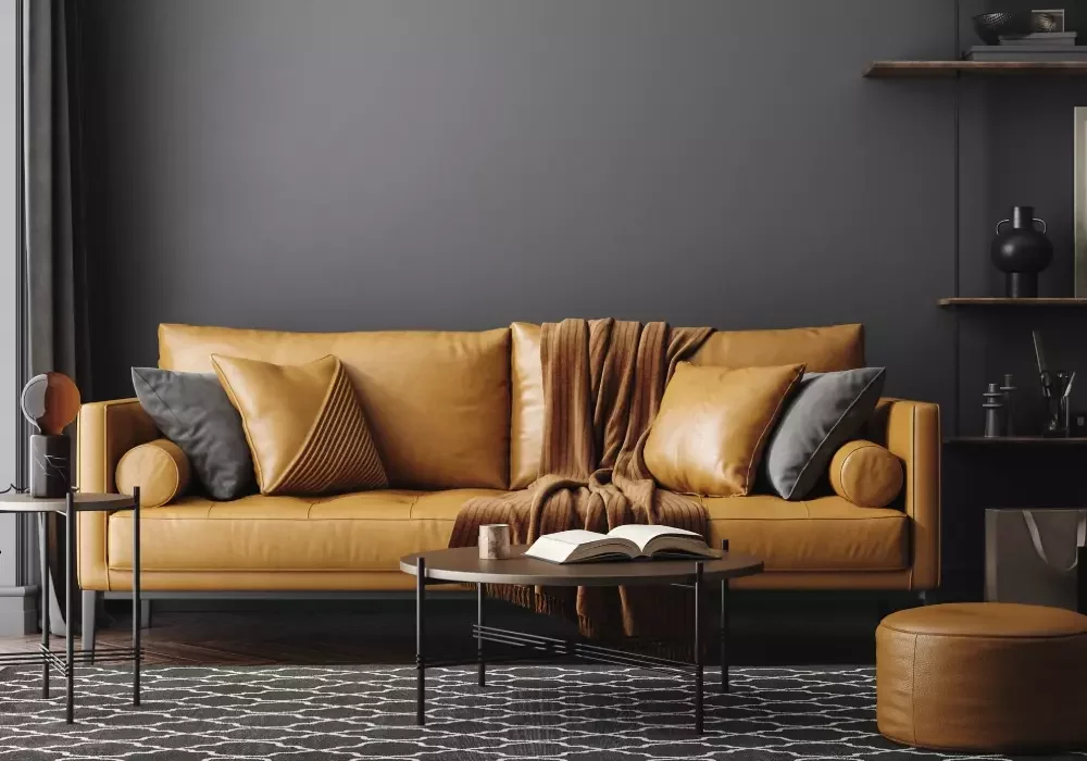 A yellow leather sofa in a living room. The walls are black.